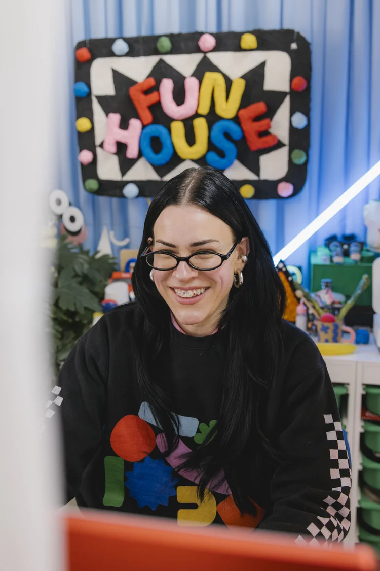 Meg smiling in front of a Fun House sign