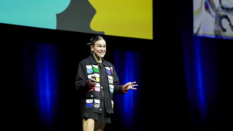 Meg on stage in front of colorful slides