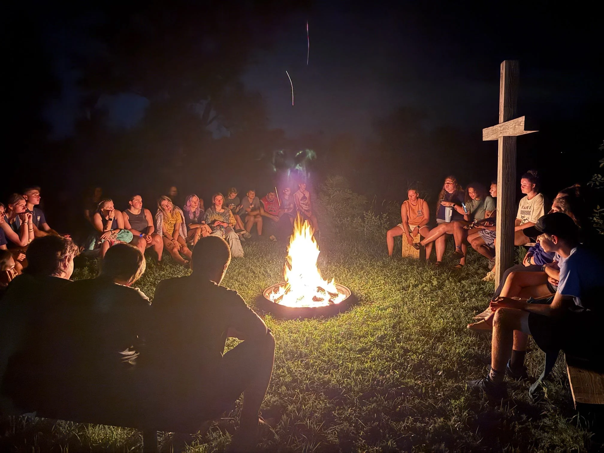 Campers gathered around a campfire at Camp Nebowa