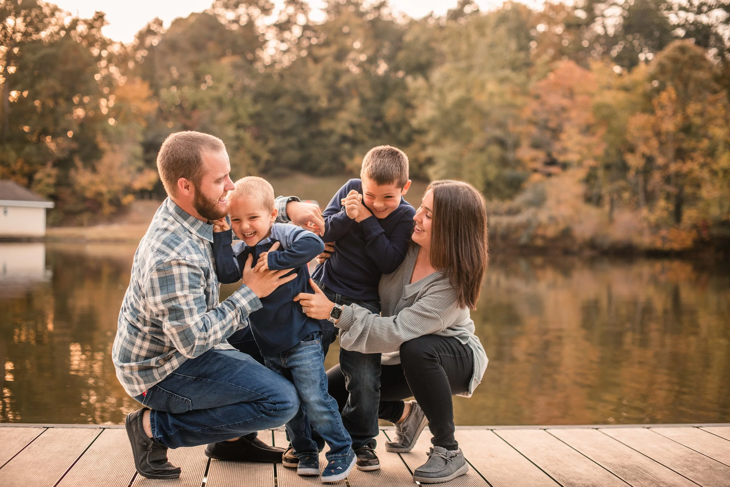 Family embracing on a dock during a golden fall session in Burlington, NC