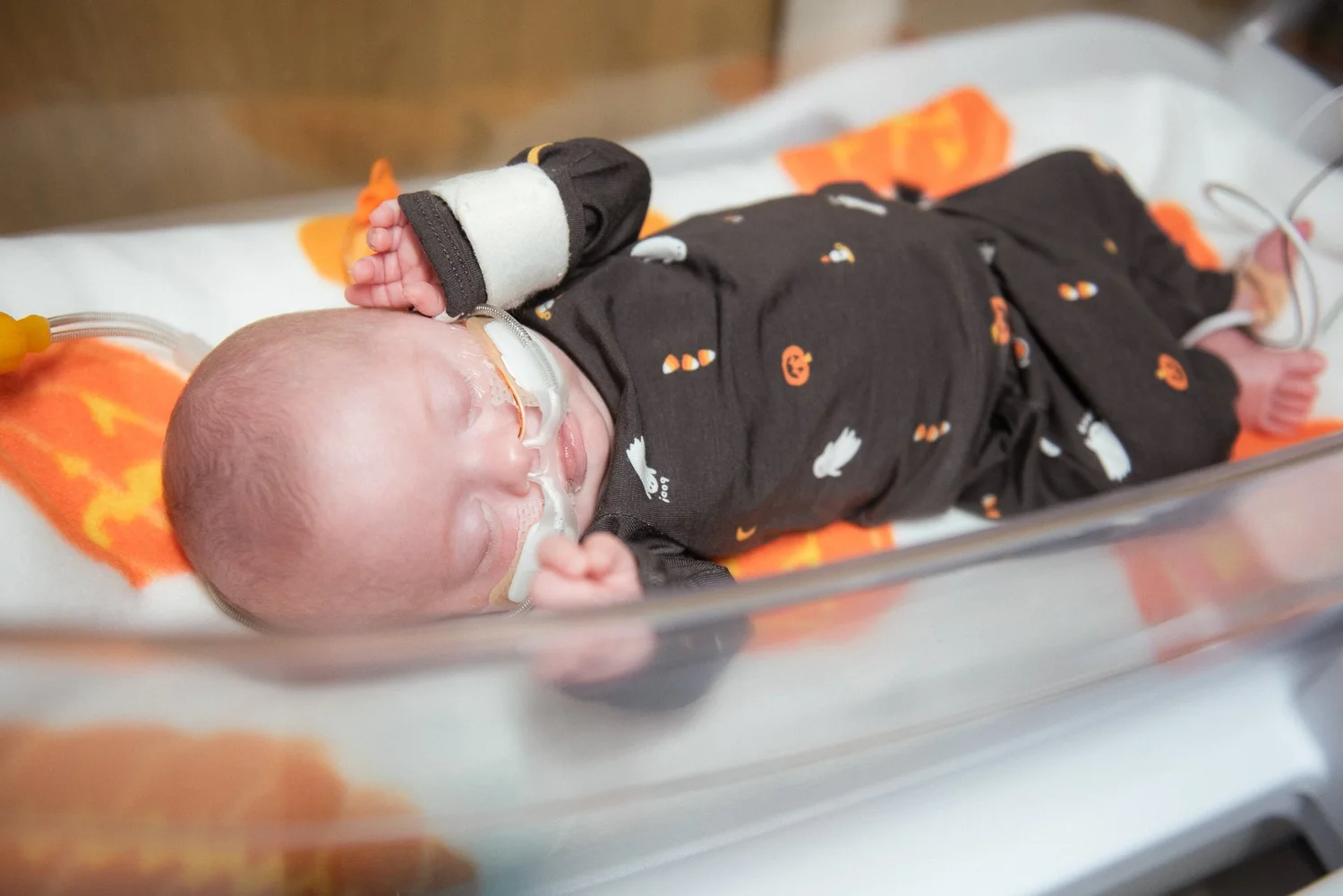 A baby in a Halloween outfit resting in the NICU