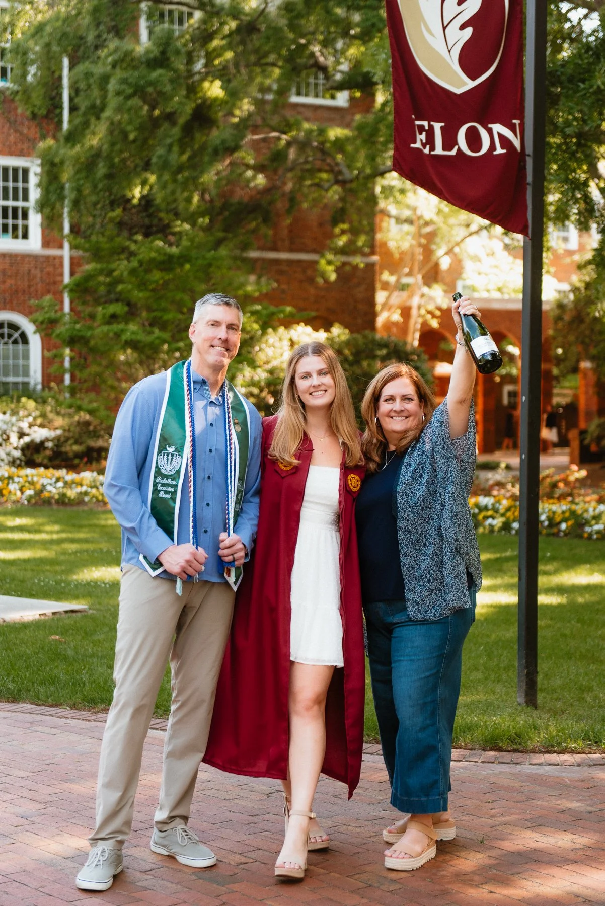Elon graduate in her gown celebrating with her mom and dad on campus