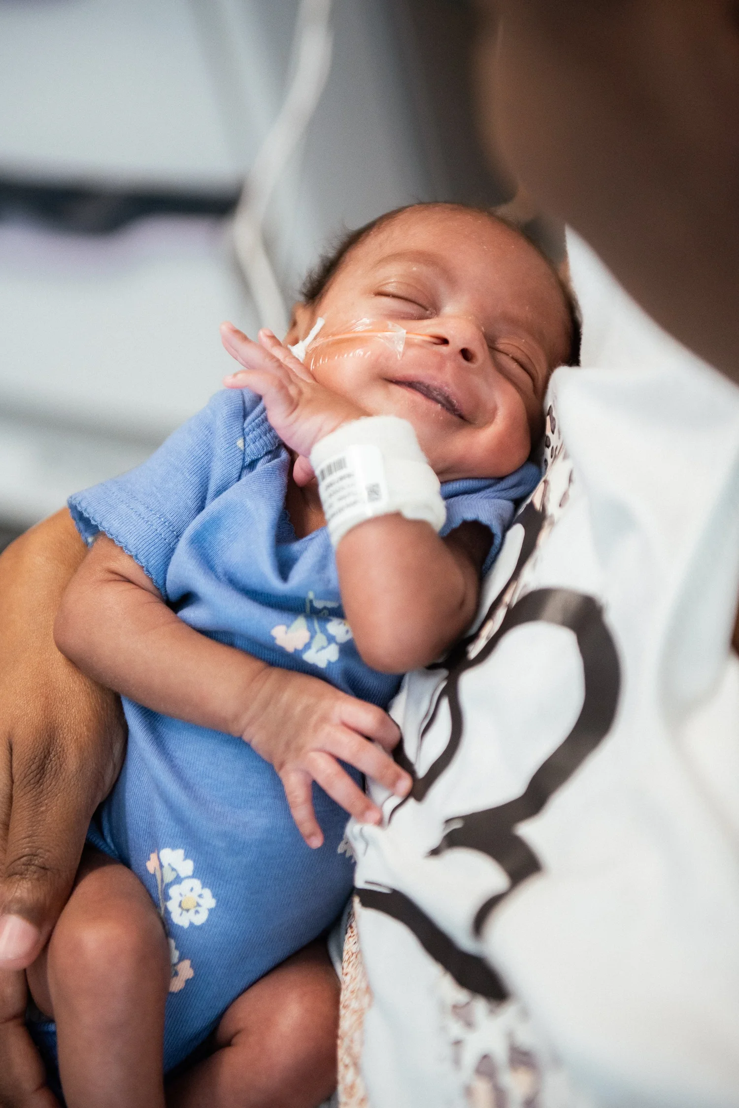 A smiling baby held in a parent's arms