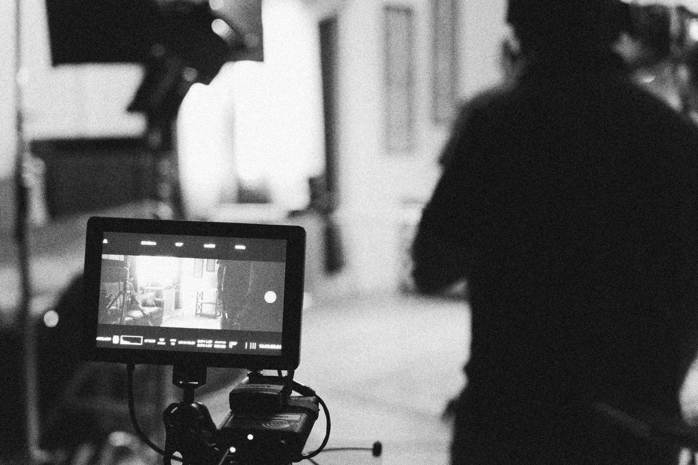 Behind the scenes on INERTIA: a field monitor glows in the foreground while a crew member stands in silhouette behind it.