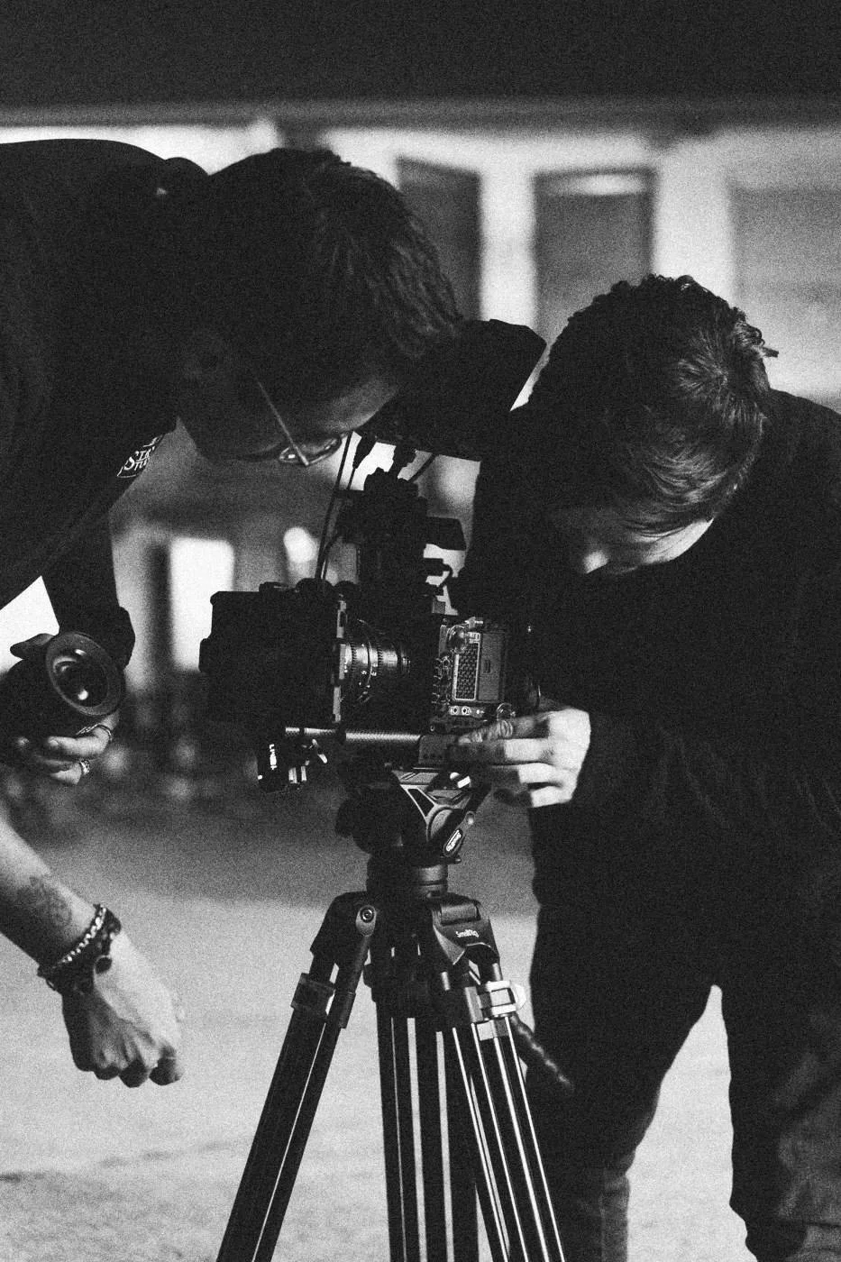 Behind the scenes on INERTIA: two crew members bent over a camera on a tripod at night.