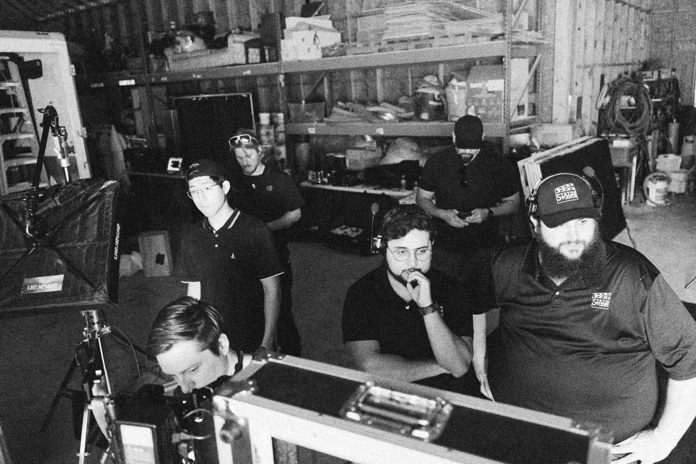 Behind the scenes on INERTIA: crew members crowd around a monitor case in a warehouse, one crouched at the screen.