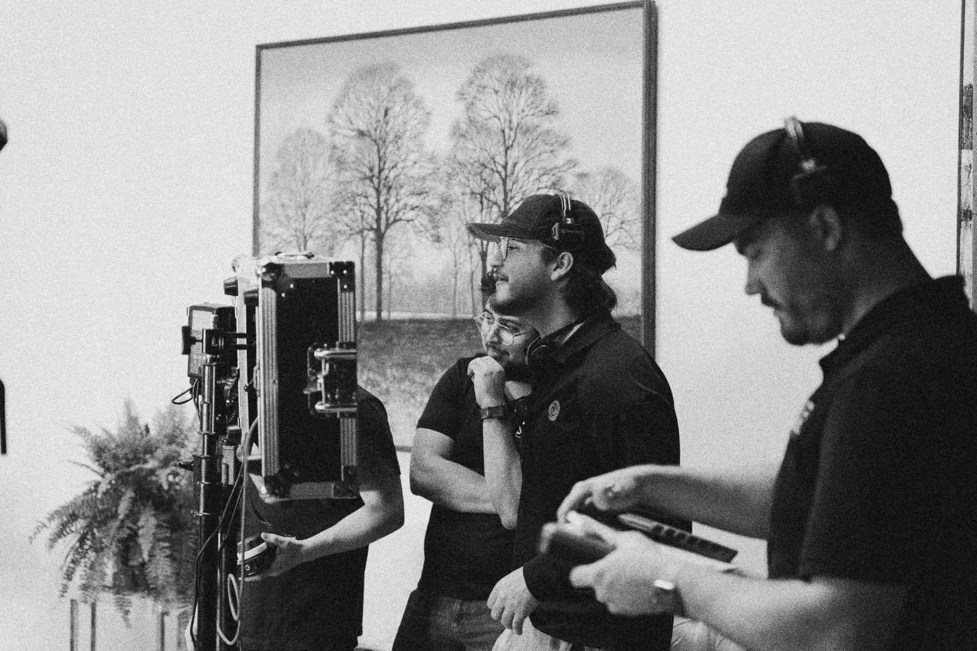 Behind the scenes on INERTIA: crew members gather around a monitor cart, one holding a camera.