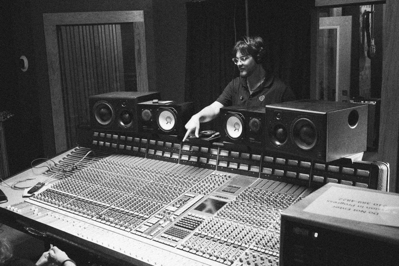 Behind the scenes on INERTIA: a crew member works at a large mixing console below studio monitors.