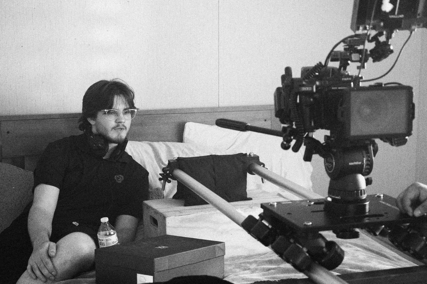 Behind the scenes on INERTIA: a crew member sits on a bed beside a camera on a slider rig.