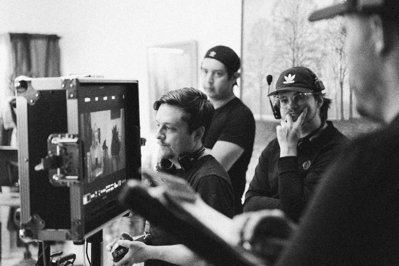 Behind the scenes on INERTIA: crew members watch a monitor showing the scene, one resting a hand on his chin.