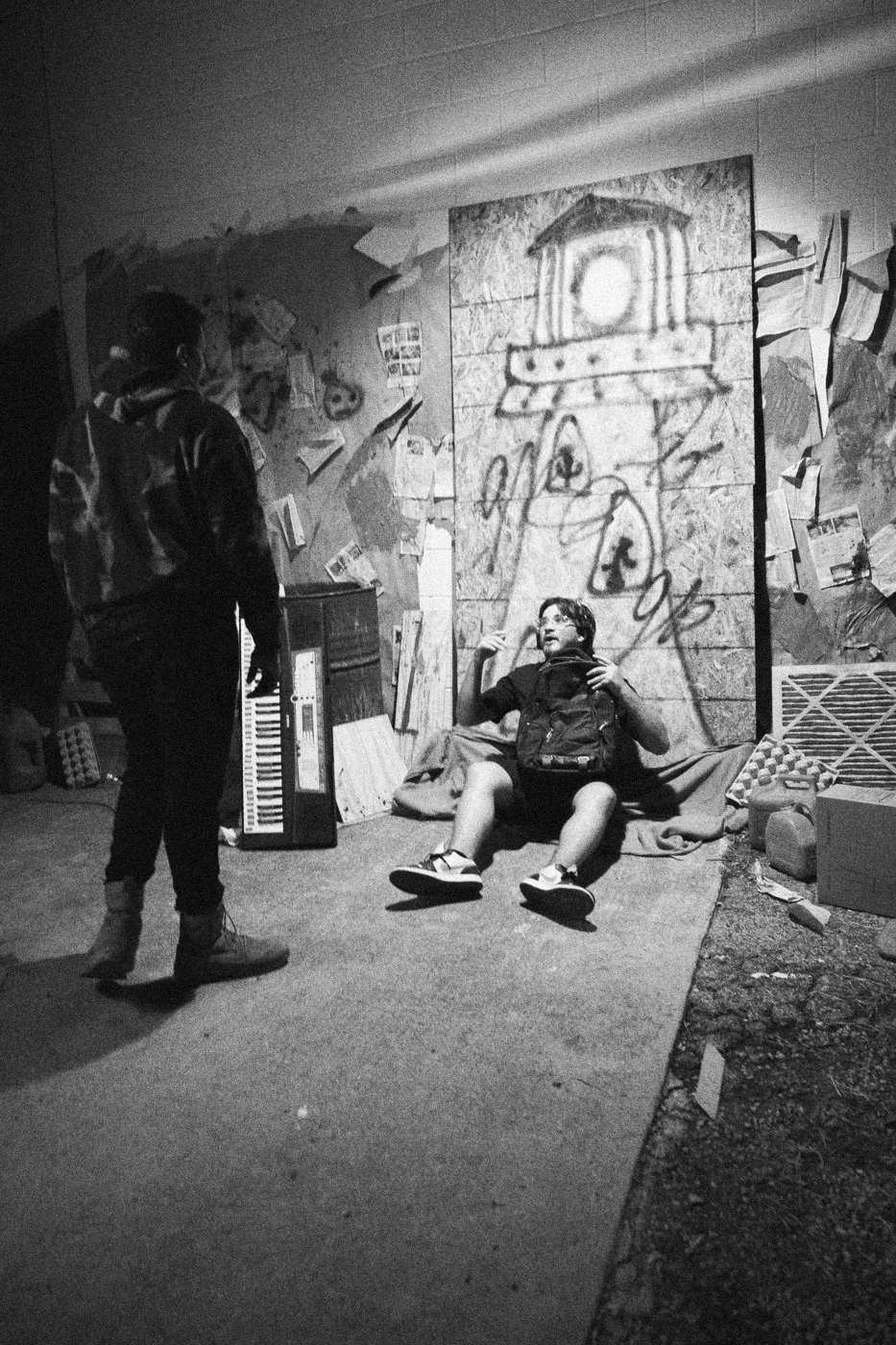 Behind the scenes on INERTIA: two people at the graffiti set at night, one lying on the ground.