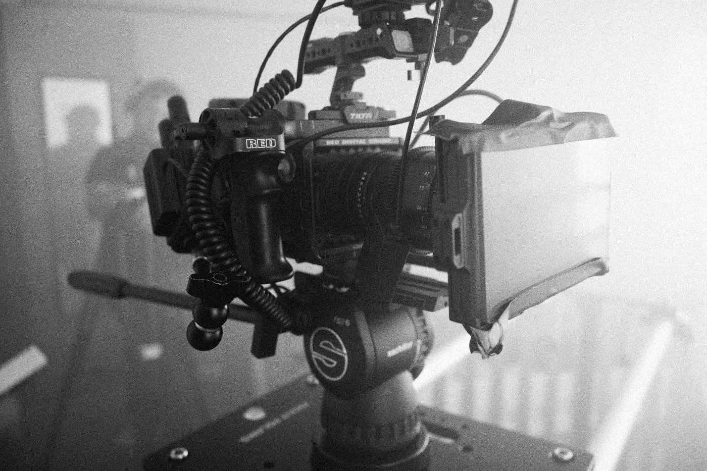 Behind the scenes on INERTIA: close detail of a rigged cinema camera on a fluid head in soft haze.