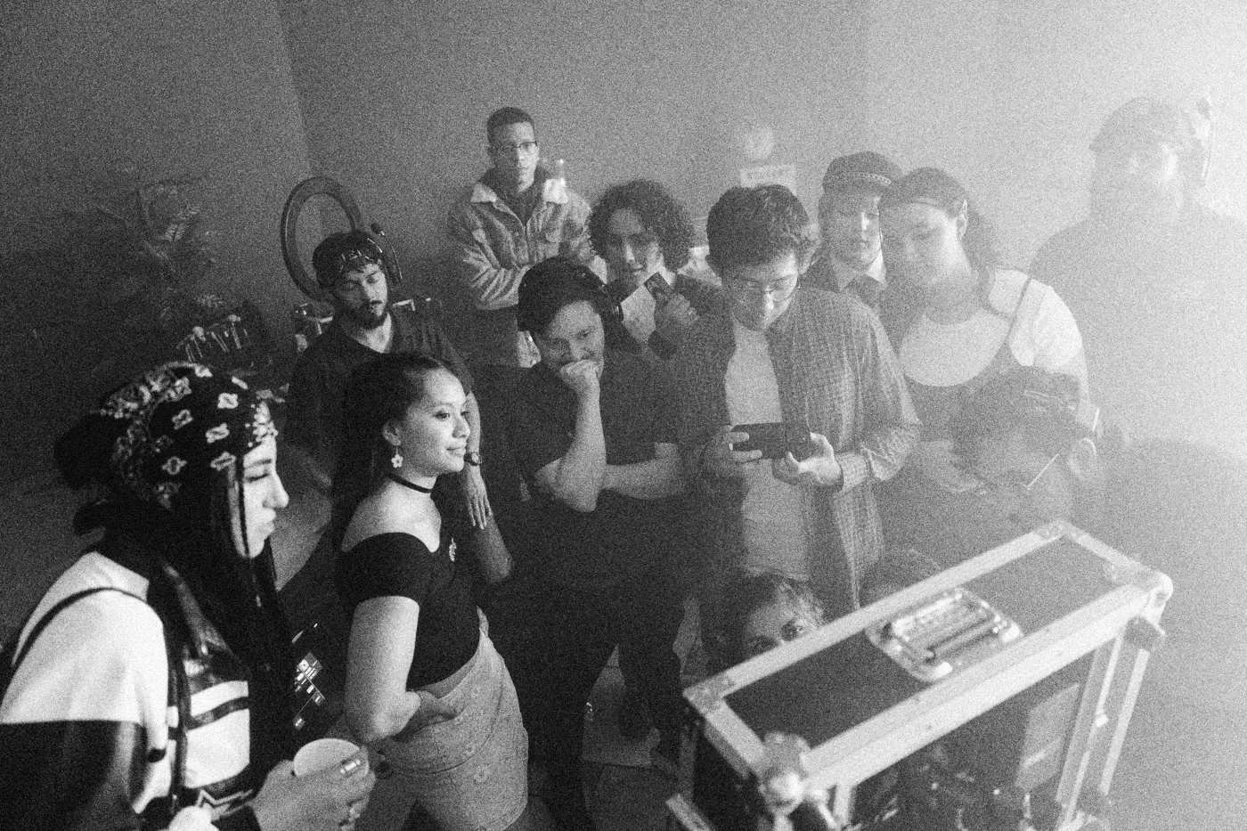 Behind the scenes on INERTIA: a crowd of party cast members gathers around a monitor case to watch playback.