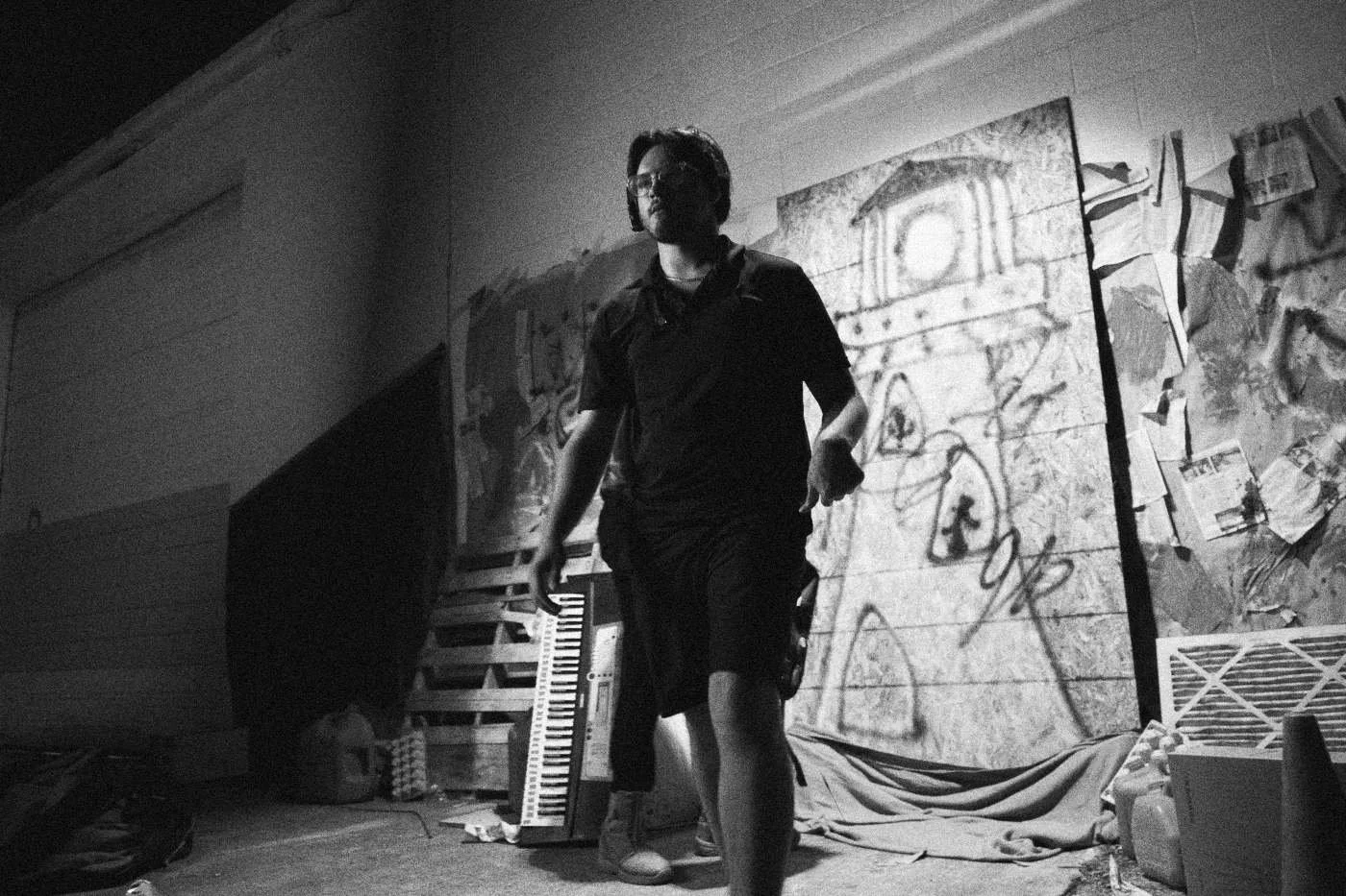 Behind the scenes on INERTIA: a crew member walks toward the camera in front of the graffiti set.