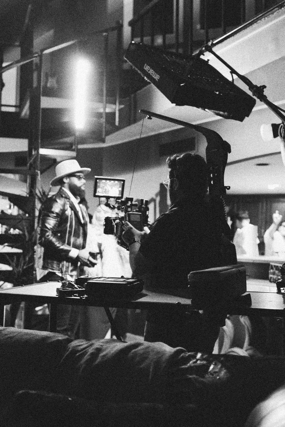 Behind the scenes on INERTIA: a camera team filming in a living room under tall lights.
