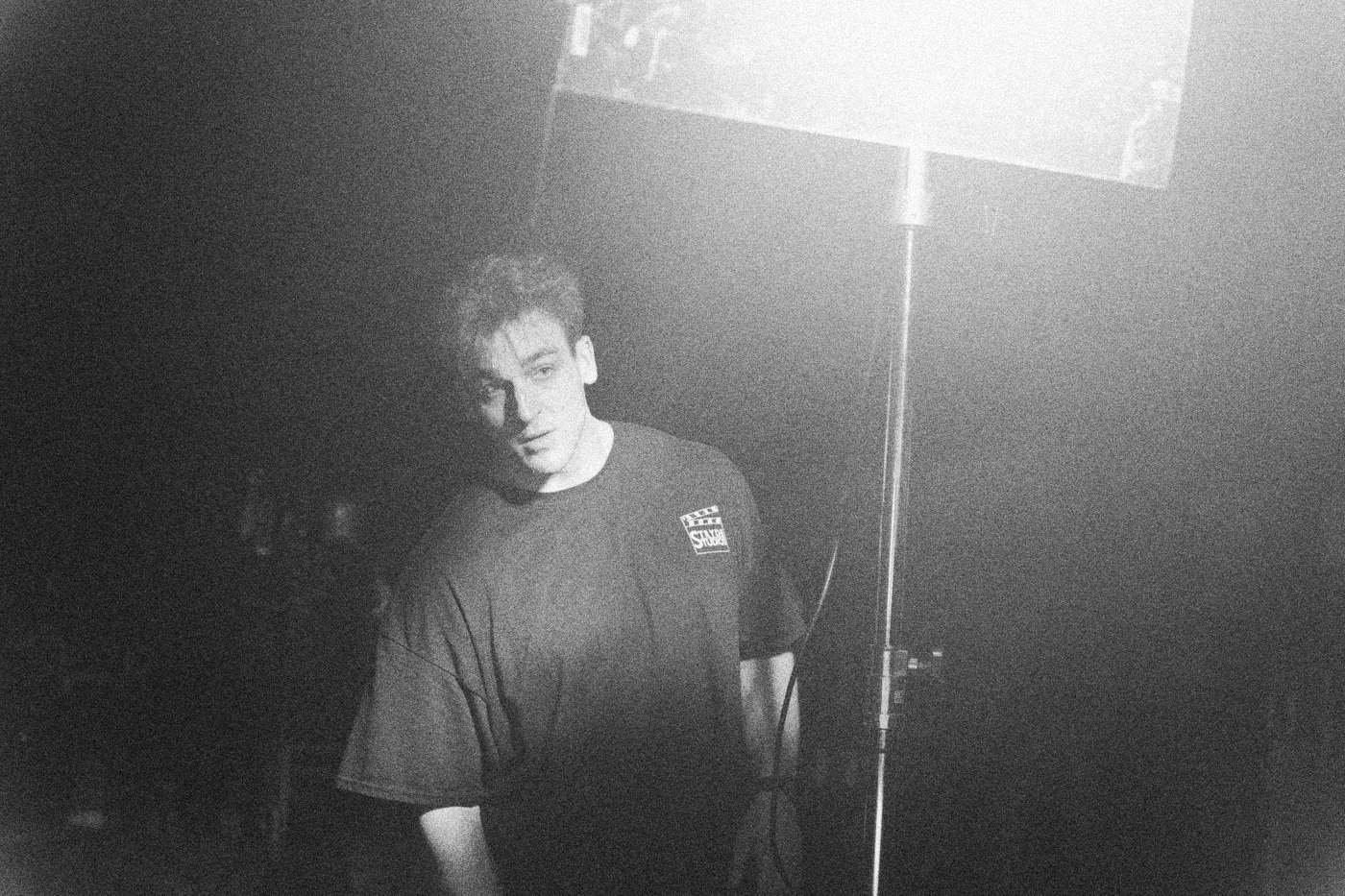Behind the scenes on INERTIA: a crew member stands under a large soft light in teal toned haze.