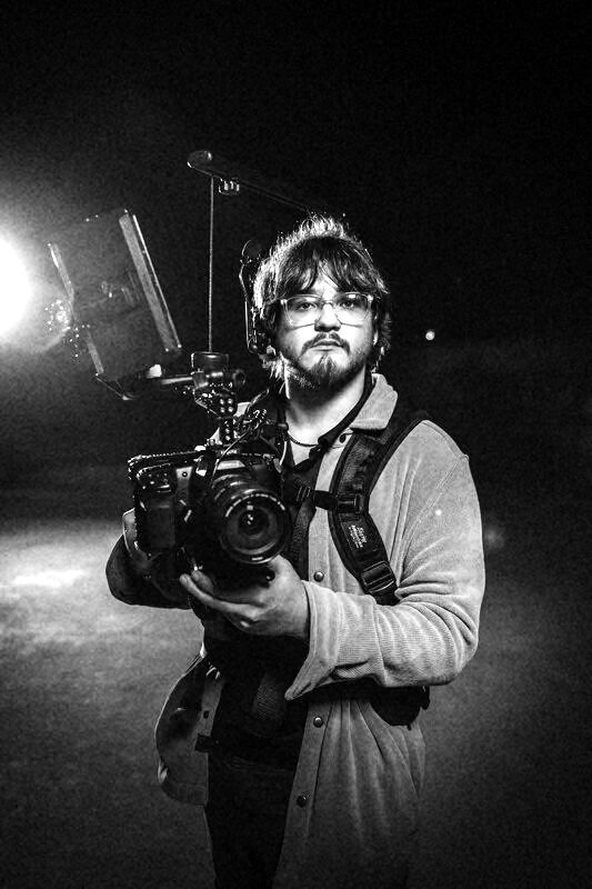 Jackson Kibby holding a cinema camera on a night exterior.