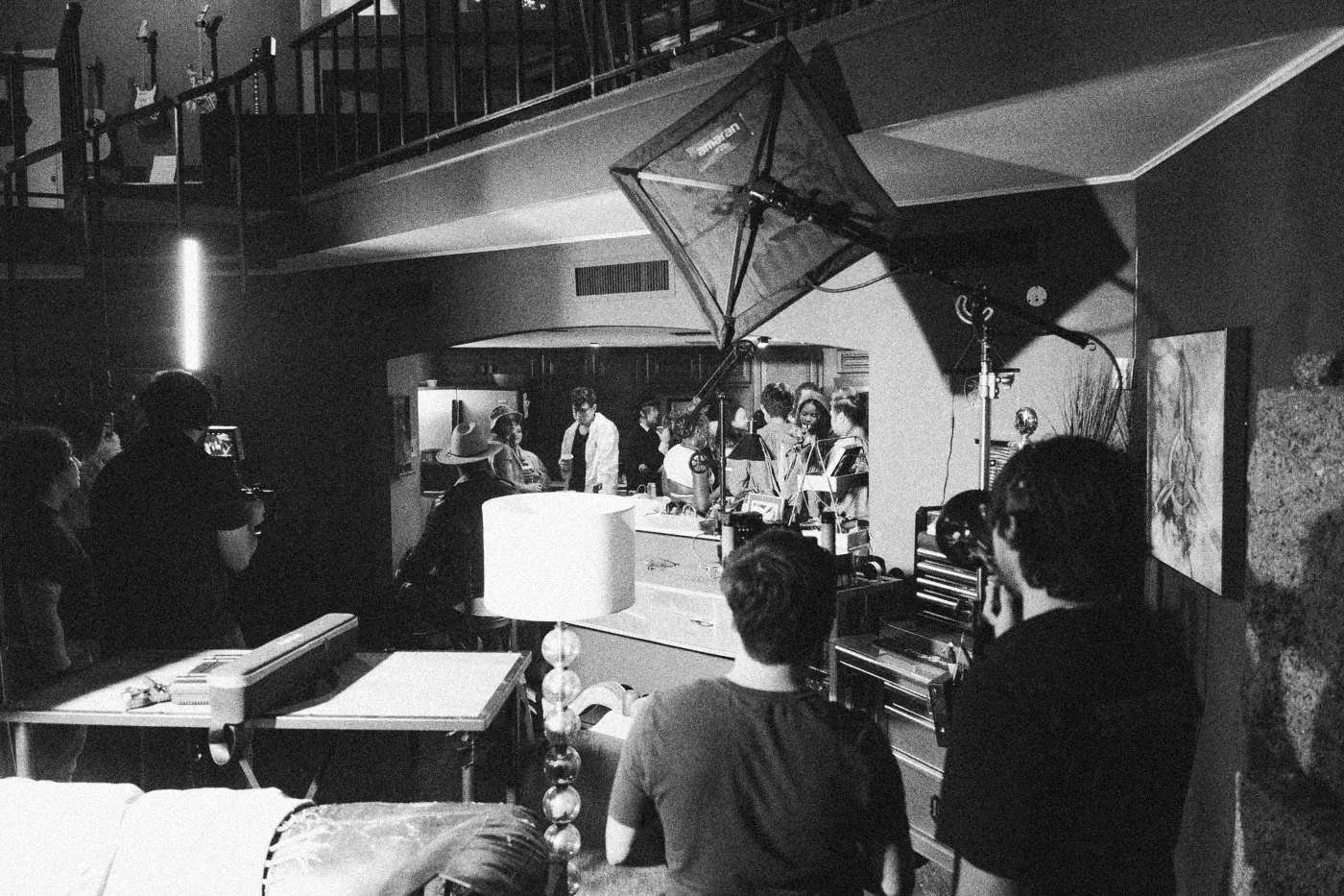 Behind the scenes on INERTIA: wide view of a house interior full of lights and crew, with a party scene visible through a doorway.