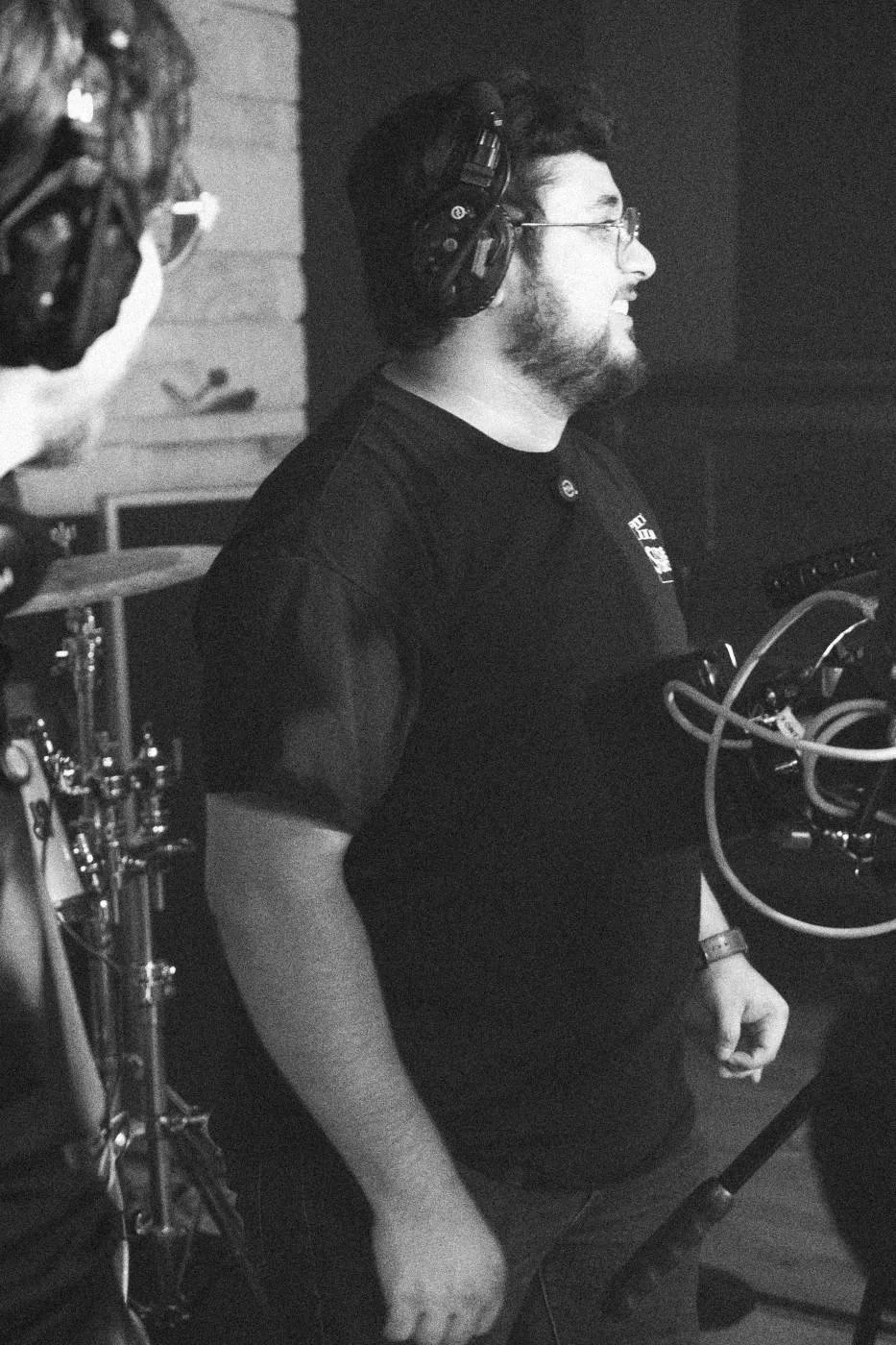 Behind the scenes on INERTIA: a crew member in a headset beside a camera rig in a studio.