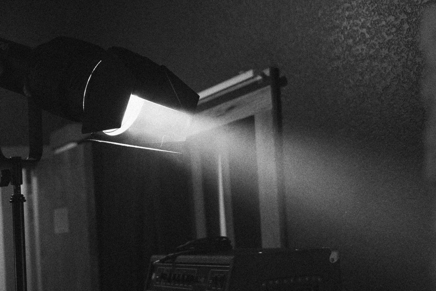 Behind the scenes on INERTIA: a single light throws a beam across a dark recording studio.