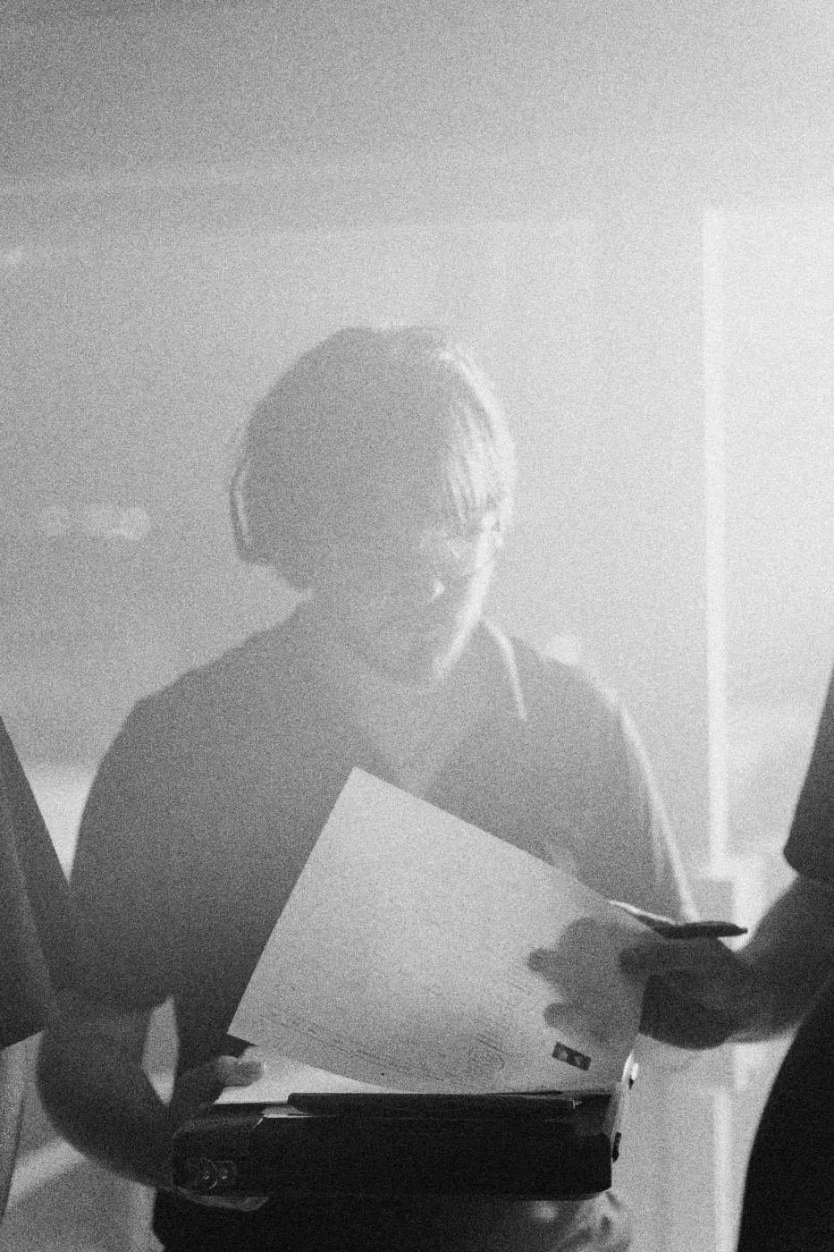 Behind the scenes on INERTIA: a crew member in a headset reading a sheet of paper on a clipboard.