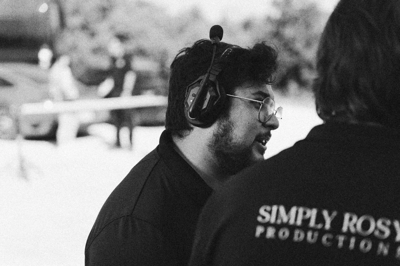 Behind the scenes on INERTIA: a crew member in a headset talks with a colleague whose shirt reads Simply Rosy Productions.