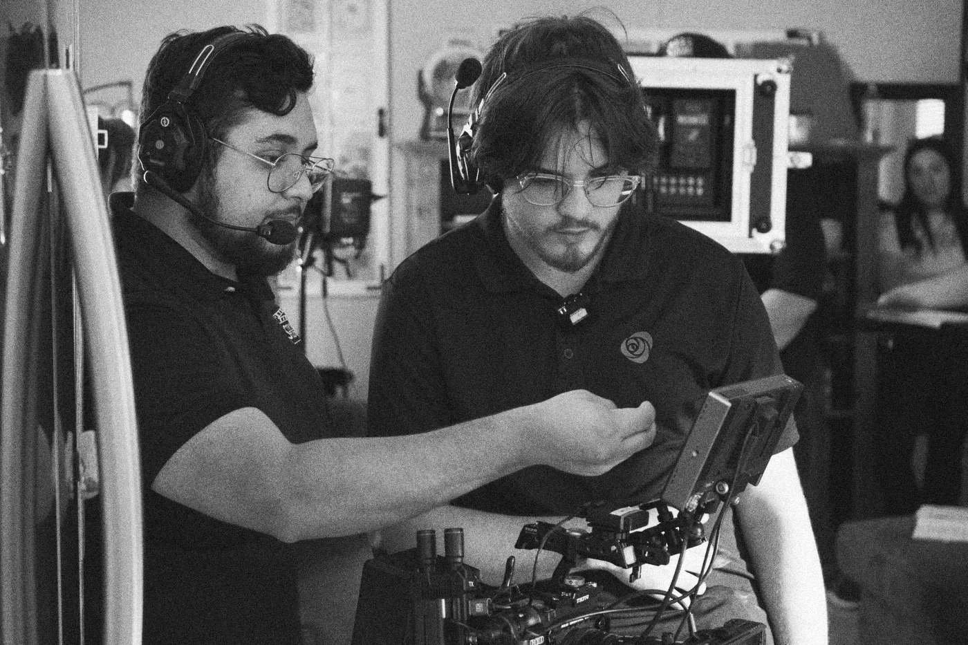 Behind the scenes on INERTIA: two crew members in headsets work together on a camera rig in a kitchen.