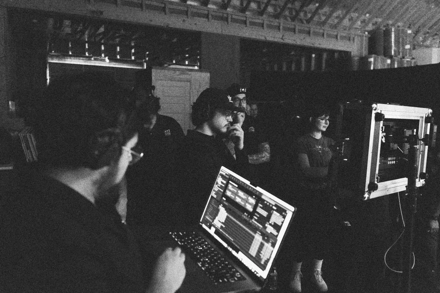 Behind the scenes on INERTIA: a crew member runs playback on a laptop while others watch a monitor behind him.