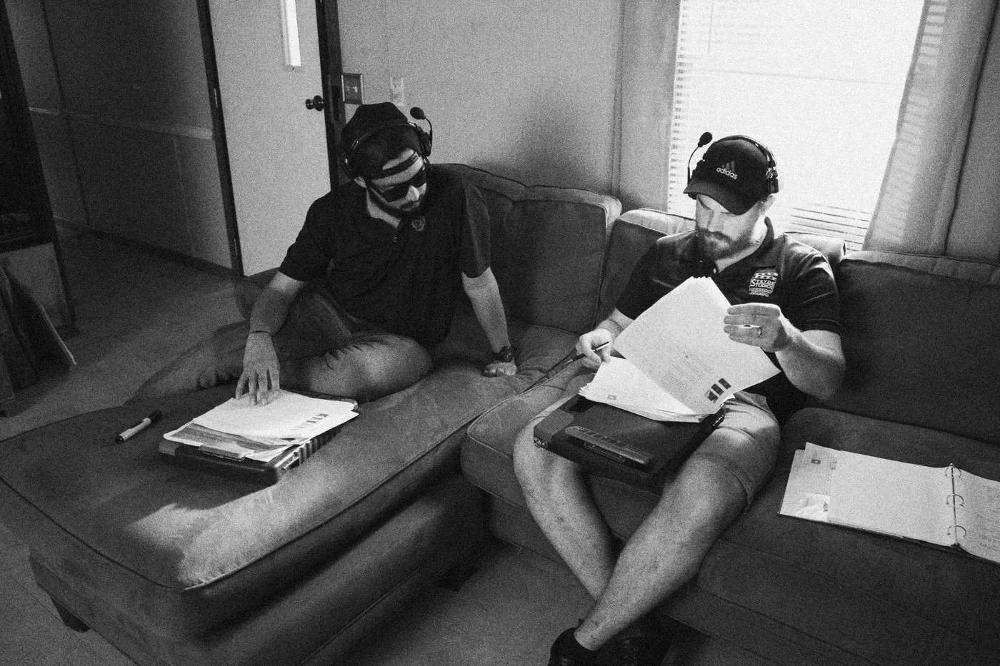 Behind the scenes on INERTIA: two crew members on a blue couch read through script pages.
