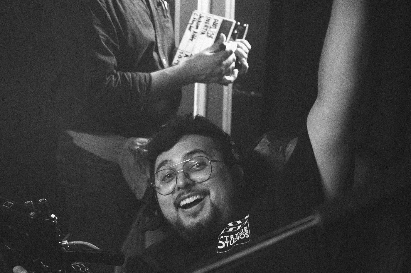 Behind the scenes on INERTIA: a crew member laughs up at the camera as the slate is held overhead.