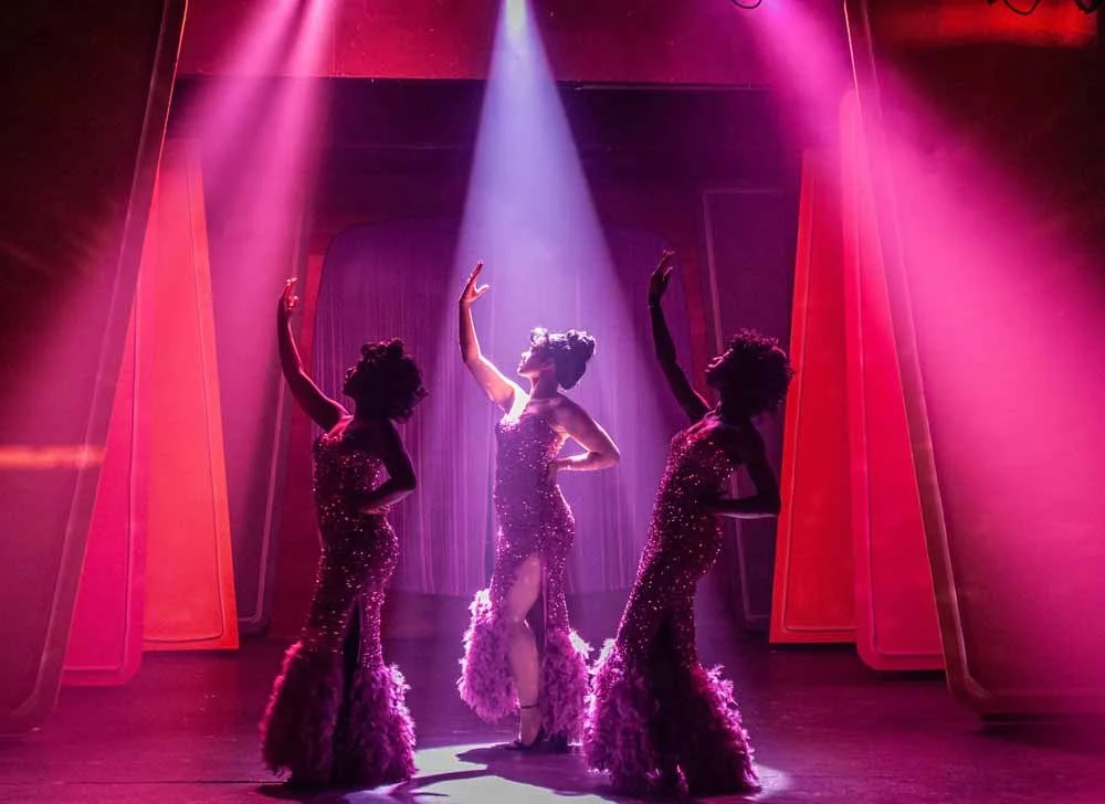 Performers silhouetted against pink stage light