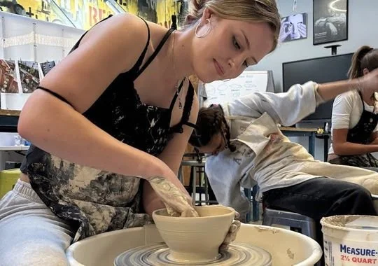 A student throwing a bowl on the pottery wheel