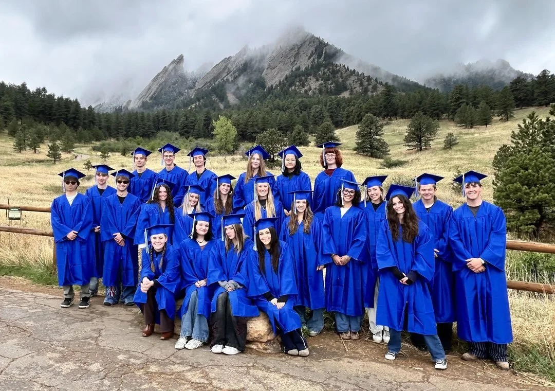 Watershed graduates in caps and gowns with the Flatirons behind them