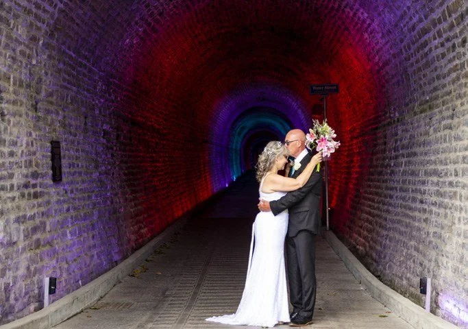 Couple kissing in a lit stone tunnel