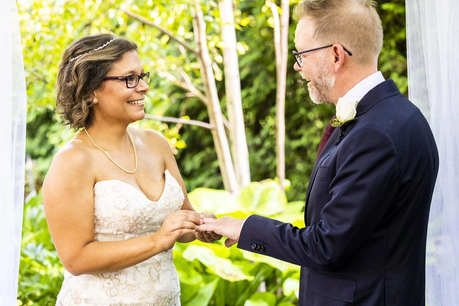 Bride smiling during the ring exchange in a garden ceremony