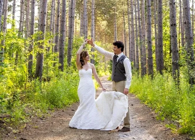 Groom twirling bride on a forest path