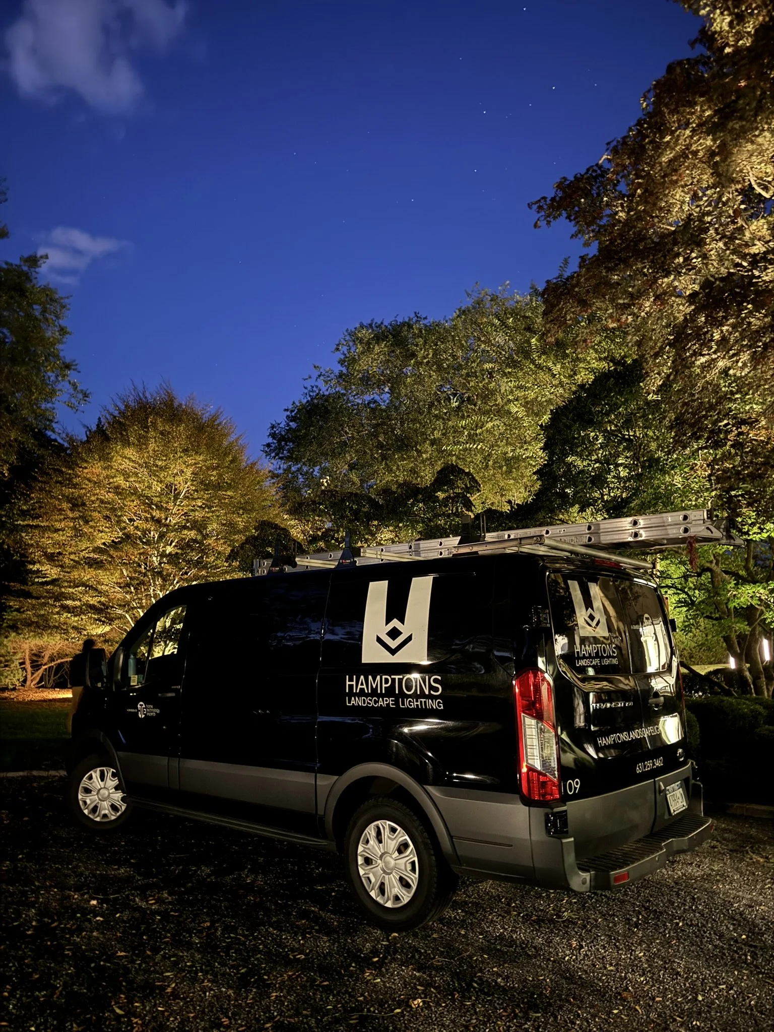 Architectural outdoor lighting highlighting a home's exterior and landscaped beds at dusk