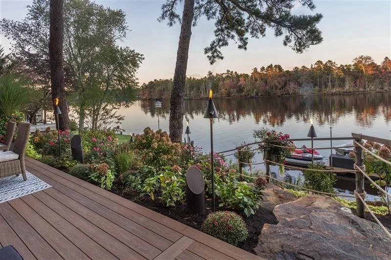 Outdoor landscape with integrated lighting and audio near a waterfront deck