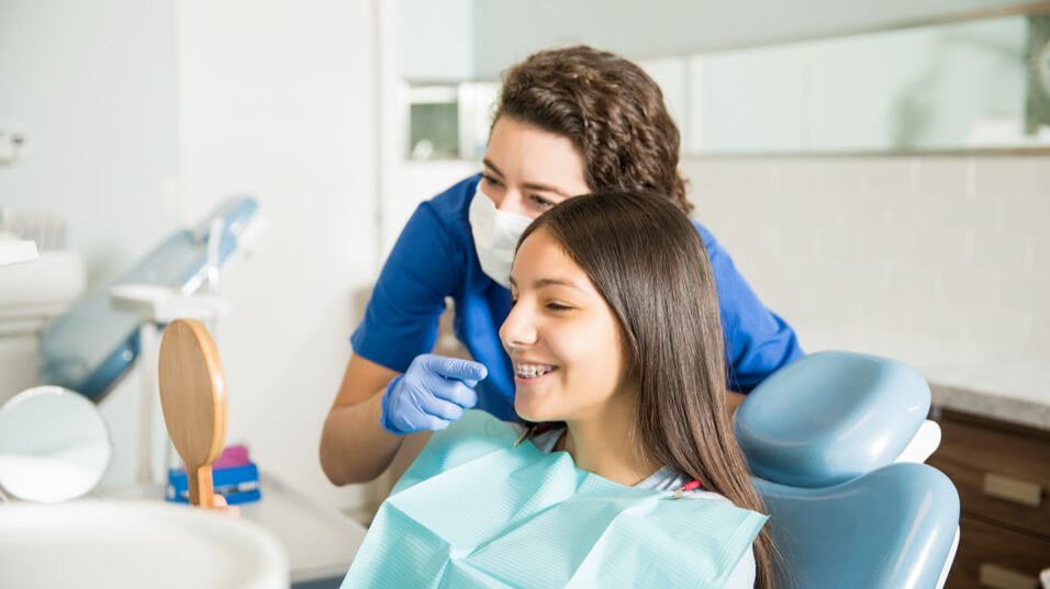 Orthodontist showing young patient her braces in Paradise NV dental office