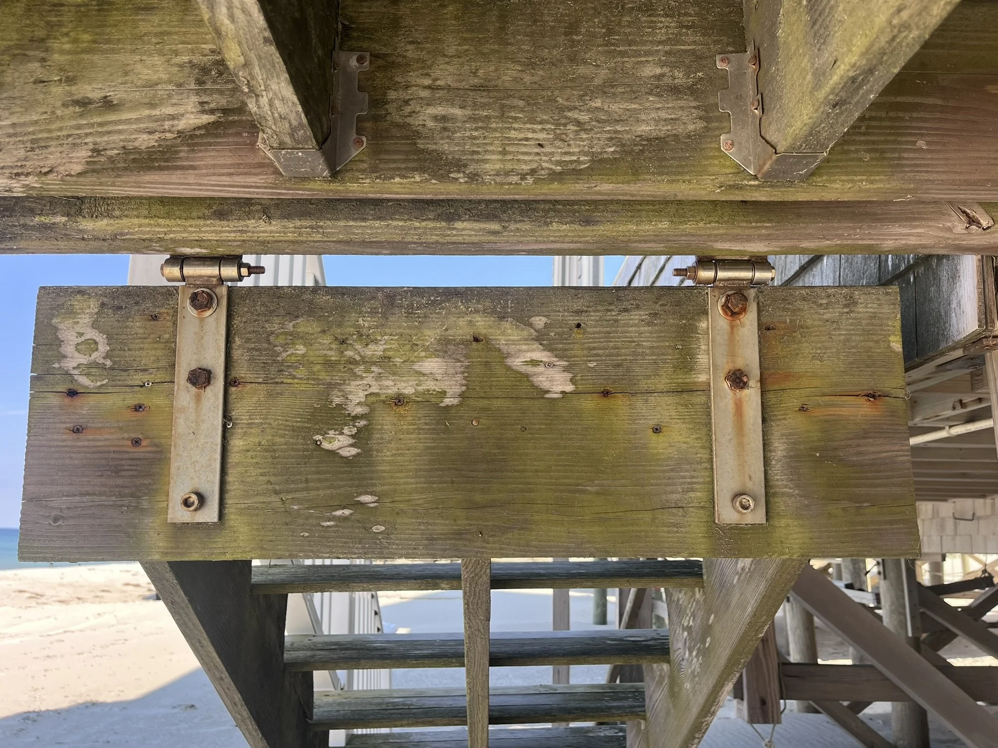 Rotted wood and corroded hardware beneath the deck