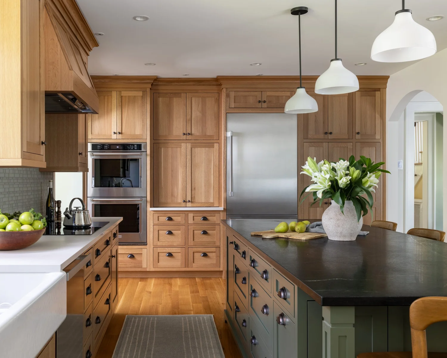 Oak kitchen with soapstone island, double ovens and farmhouse sink