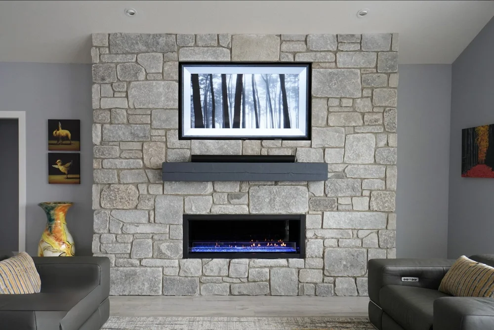 Fond du Lac in tumbled ashlar fills a living room chimney breast above a linear firebox and dark mantel.