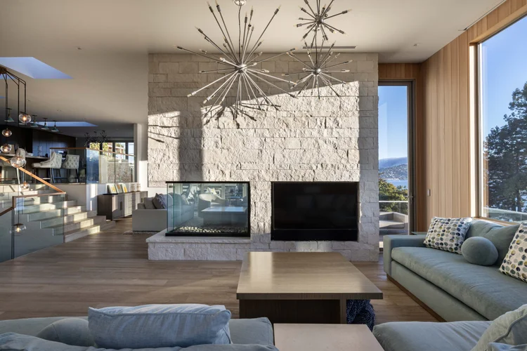 White coursed veneer and a white honed mantel framing a stone fireplace in a residential interior.