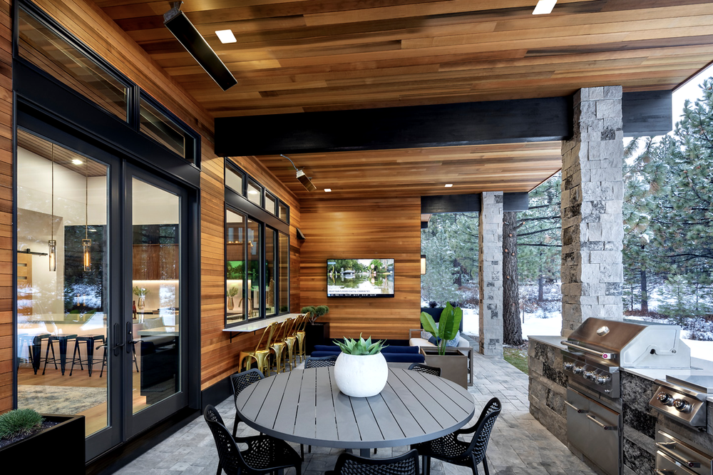 A Charcoal veneer column stands beside the built-in grill of an outdoor kitchen under a cedar ceiling.