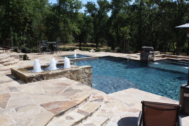 Split-face Desert Mountain veneer above natural-finish irregular pavers at a poolside.