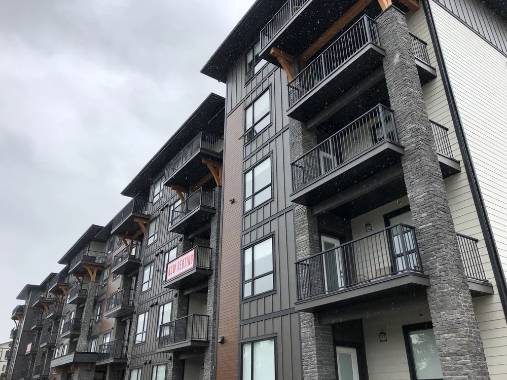 Silver Pearl columns carry the balcony bays of an apartment building under a flat gray sky.