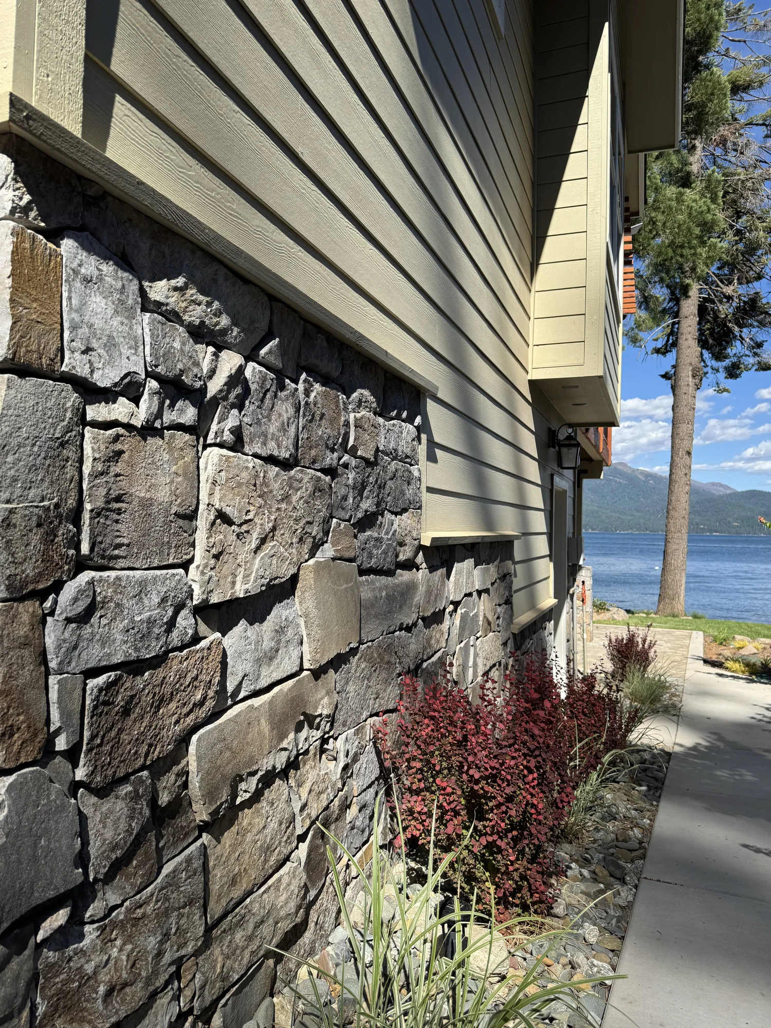Gallatin River veneer at the base of a home beside a stone walkway.