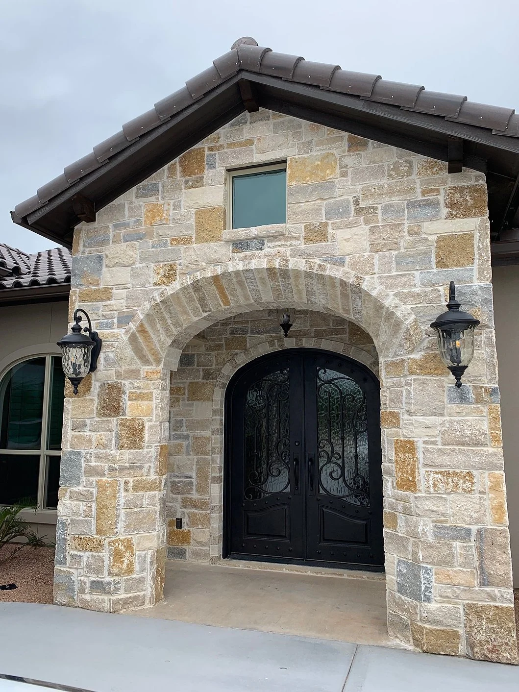 Tuscany Bronze field veneer on a facade and entry in split and natural faces with flush joints.