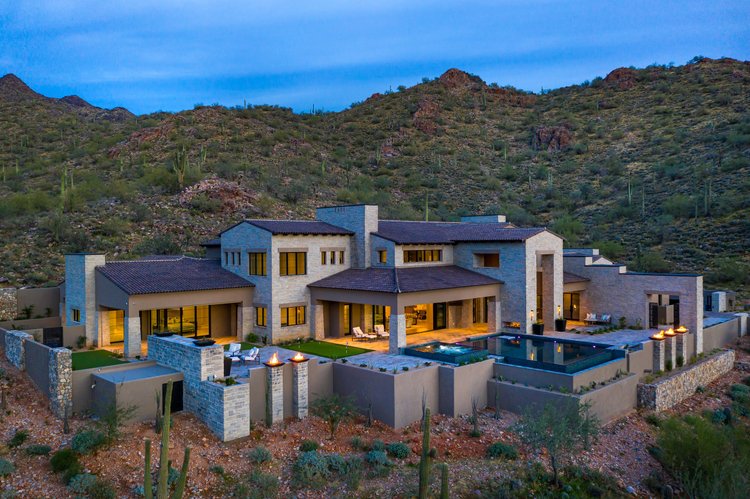 Gray Variegated walls a desert house at dusk, the pool terrace glowing below a saguaro ridge.