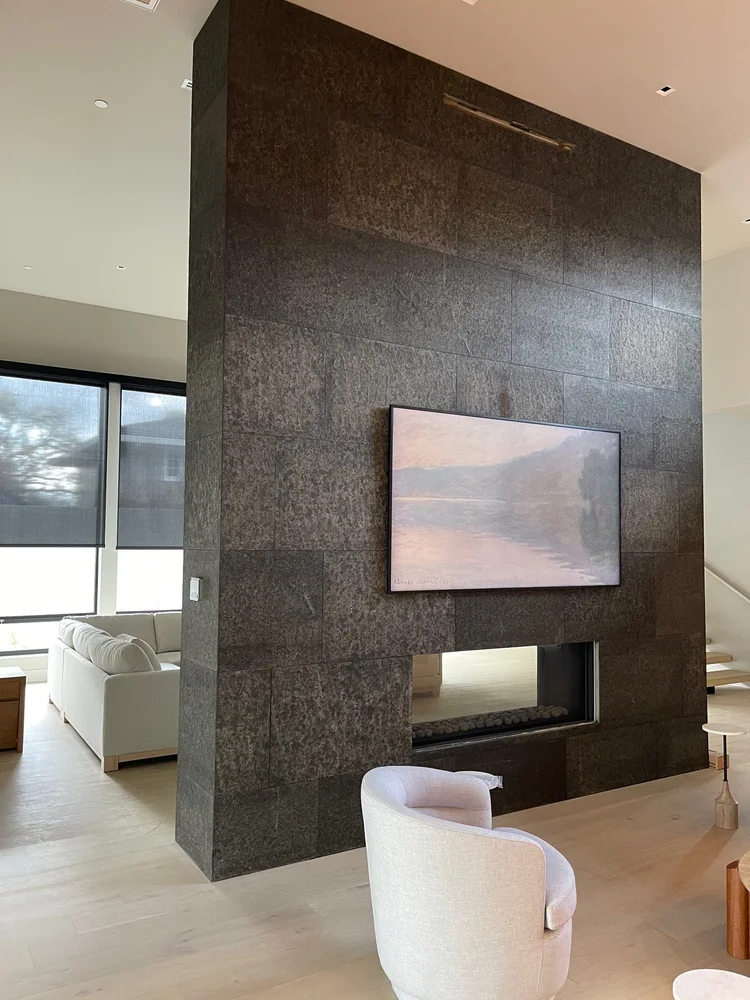 A full-height Black Basalt chimney holds the television above a linear fireplace.